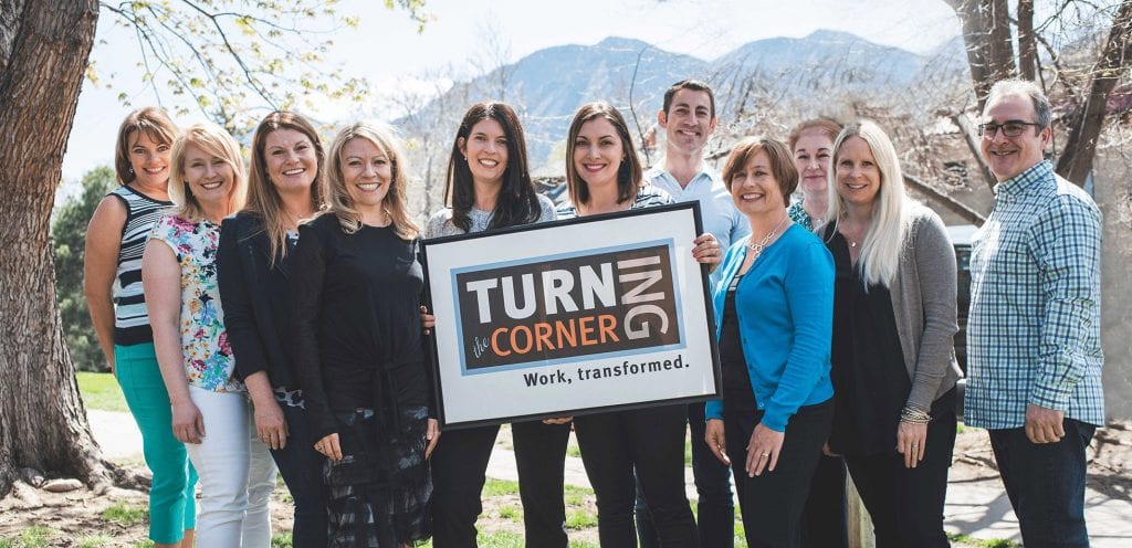 group of people in a park holding a "Turning the Corner" sign